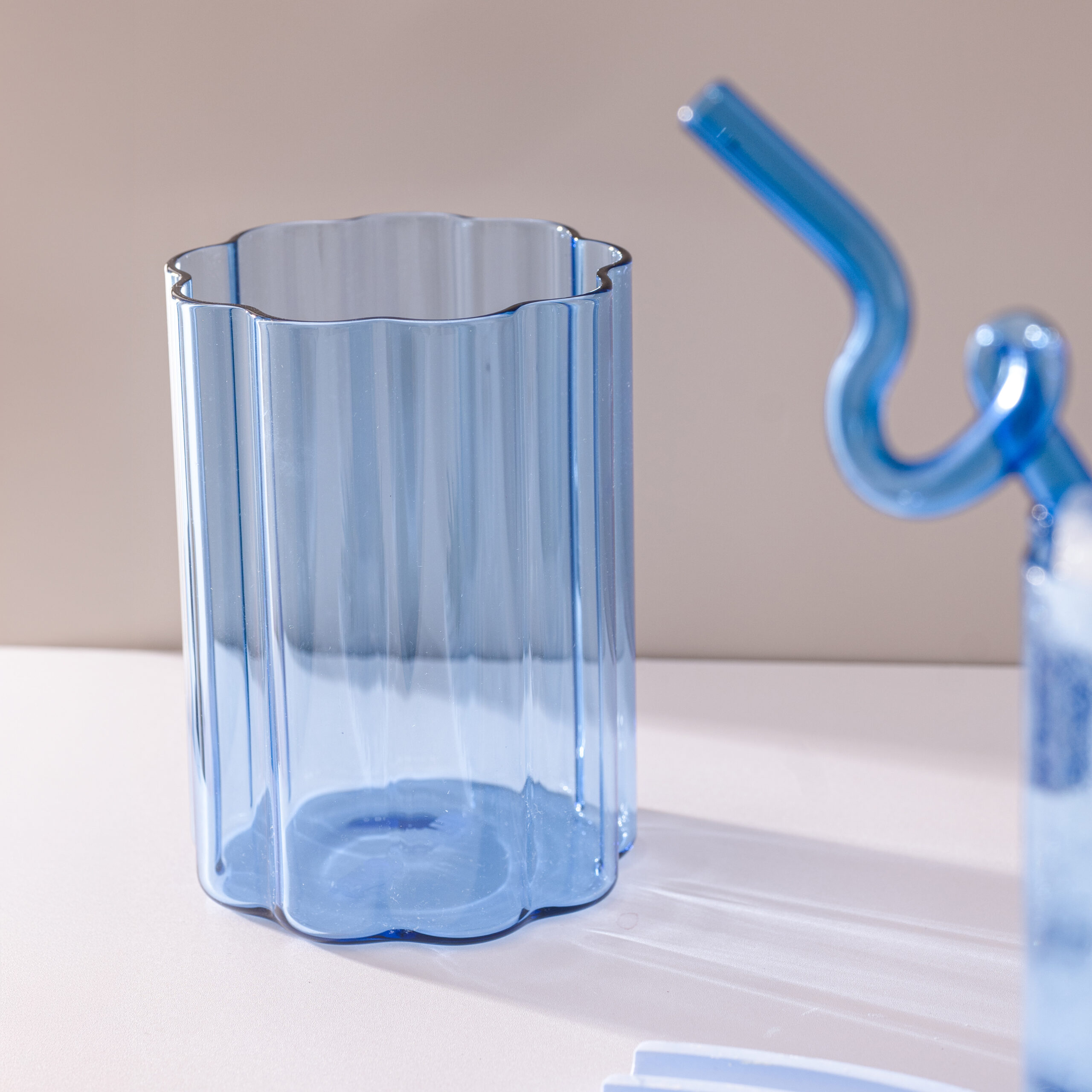 Empty Blue Ripple Glass showcasing its elegant vertical ripple texture on a white tabletop.