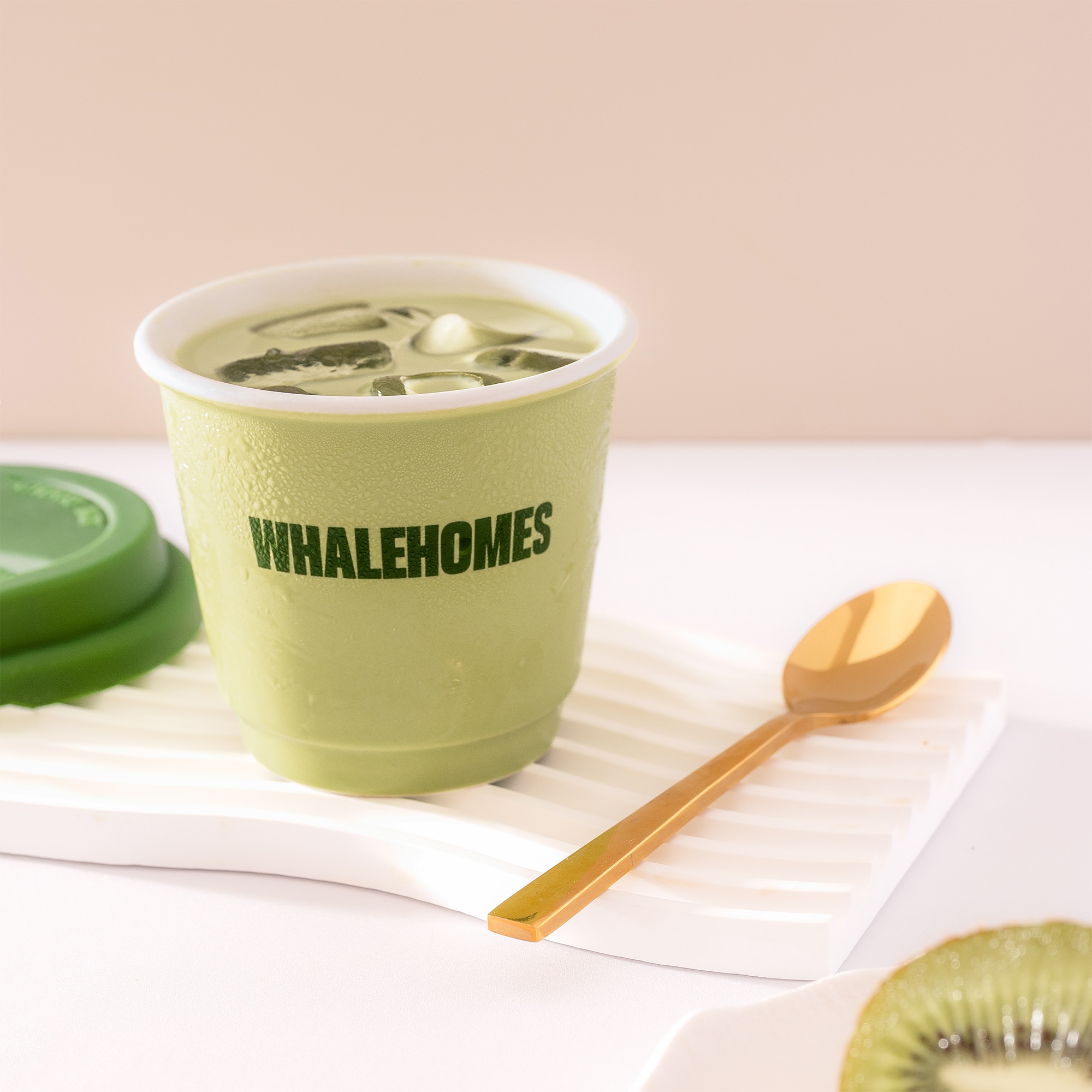 Close-up of the WHALEHOMES logo on the Green Everyday Cup with refreshing iced matcha.
